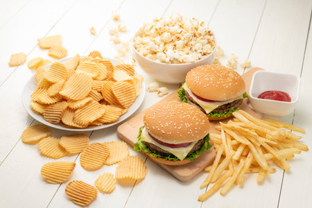 Junk food image. Hamburger with french fries, potato chips and popcorn.の写真素材