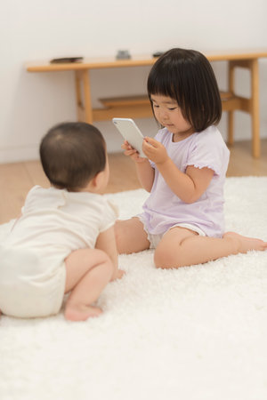 Little sisters taking pictures with a smartphone and playingの写真素材