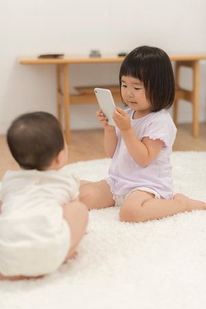 Little sisters taking pictures with a smartphone and playingの写真素材