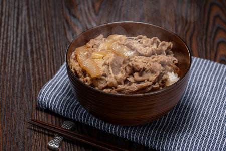 Bowl of rice topped with cooked beef and onions.の写真素材