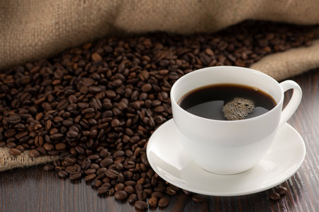 Coffee in a cup against the background of roasted coffee beansの写真素材