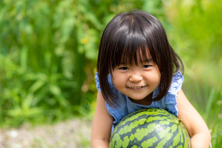 Little girl eating freshly picked watermelon in the fieldの写真素材