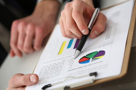 Group of people deliberate on problem with clipboard pad closeup. White collar check money papers, stock exchange market, earnings list, partnership agreement discussion conceptの写真素材