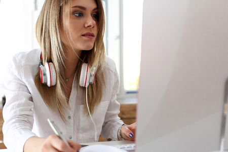 Beautiful woman making notes with silver pen while working on computer pc closeup. Management training course, leader ambition, modern remote school, self development and perfection conceptの写真素材