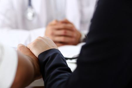 Young couple hold hands together in doctor office closeup. Motherhood and child delivery, new life or abortion, therapeutist reception service, physical, hope emotion, hospital and clinic conceptの写真素材