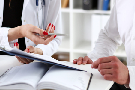 Female doctor hand hold silver pen and showing pad. Physical agreement form signature, disease prevention, ward round reception, consent contract sign, prescribe remedy, healthy lifestyle conceptの写真素材