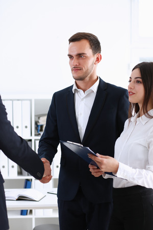 A helper of an Arab businessman organized a meeting with an investor for him, they shake hands with each other and anticipate the profits from joint actionsの写真素材