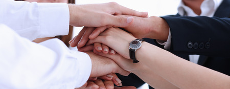 Group of people in suits crossed hands in pile for win closeup. White collar leadership, high five, cooperation initiative achievement, corporate life style, friendship deal, heap, stack conceptの写真素材