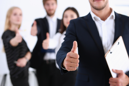 Handsome smiling man showing OK or approval sign with thumb up in creative people office portrait. High level and quality service, job offer, excellent education, advisor, serious business conceptの写真素材