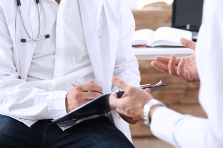 Male medicine doctor with clipboard pad in hands examine patient and prescribe remedy. Exam, visitor reception, er, disease prevention, ward round, visit check, 911, healthy lifestyle conceptの写真素材