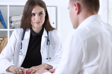 Beautiful smiling female doctor talk with patient about his history list. Physical, exam, er, anamnesis communication, disease prevention, ward round, 911, prescribe remedy, healthy lifestyle conceptの写真素材