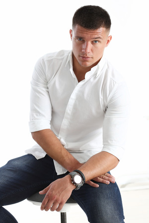 A man holds his hand to his chin against a white background. Pretending to look at the cameraの写真素材