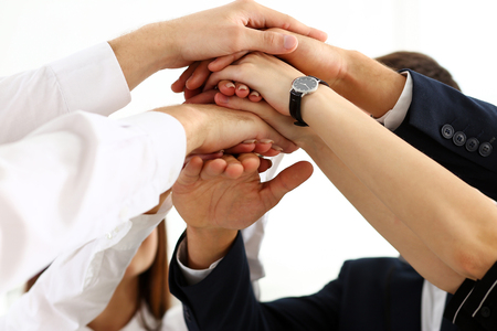 Group of people in suits crossed hands in pile for win closeup. White collar leadership, high five, cooperation initiative achievement, corporate life style, friendship deal, heap, stack conceptの写真素材