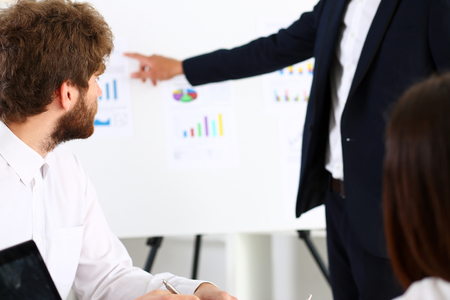 Group of people deliberate on white board problem in office closeup. Graph consult, idea participate, creative talk, review situation job, document explain council, train, successful decision conceptの写真素材
