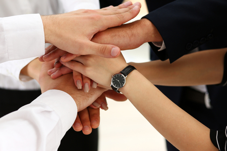 Group of people in suits crossed hands in pile for win closeup. White collar leadership, high five, cooperation initiative achievement, corporate life style, friendship deal, heap, stack conceptの写真素材