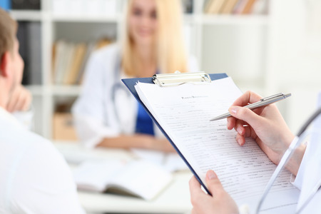 Female doctor hand hold silver pen filling patient list at clipboard pad closeup. Physical, exam, er, disease prevention, ward round, visit check, 911, prescribe remedy, healthy lifestyle conceptの写真素材
