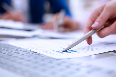 Female hand point silver pen to graph on seminar. Bank credit, loan money, invest, tax situation review, income calculation form, white collar train, investment audit, board members session conceptの写真素材