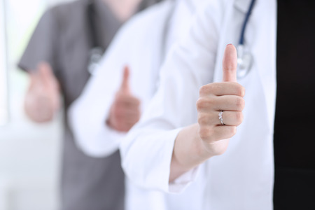 Group of doctor hands show OK or approval sign with thumb up closeup. High level service, best treatment, 911, healthy lifestyle, satisfied patient, therapeutist consultation, physical conceptの写真素材