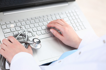 Medicine doctor hand press key on laptop computer pc keyboard at workplace in office closeup. Medic instrument shop, modern communication PC, surfing, remote aid, read news, exams preparation conceptの写真素材