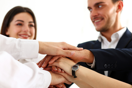 Group of people in suits crossed hands in pile for win closeup. White collar leadership, high five,...