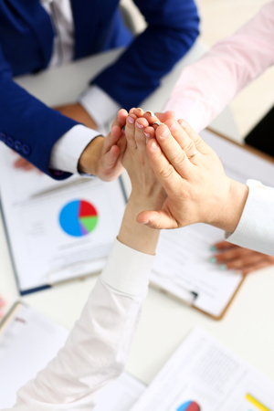 Group of people in suits crossed hands in pile for win closeup. White collar leadership, high five, cooperation initiative achievement, corporate life style, friendship deal, heap, stack conceptの写真素材