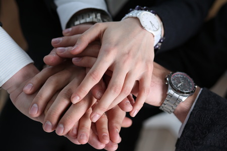 Group of people in suits crossed hands in pile for win closeup. White collar leadership, high five, cooperation initiative achievement, corporate life style, friendship deal, heap, stack conceptの写真素材