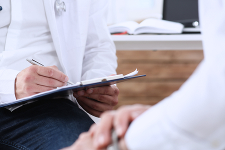 Male medicine doctor with clipboard pad in hands examine patient and prescribe remedy. Exam, visitor reception, er, disease prevention, ward round, visit check, 911, healthy lifestyle conceptの写真素材