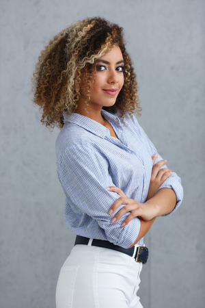 Beautiful black woman portrait. Worth a gray background and smiling beauty fashion style mulatto curly hair with white strands view of the eye in the cameraの写真素材