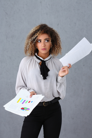 Beautiful black woman portrait. Holds paper documents with financial statistics fashion style mulatto curly hair with white locks eye view of the camera lot of workの写真素材