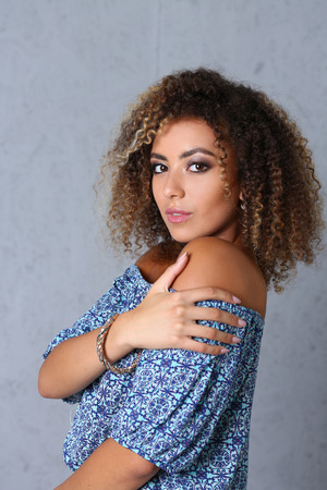 Beautiful black woman portrait. It's a gray background and does not smile beauty fashion style mulatto curly hair with white strands look the eye into the cameraの写真素材