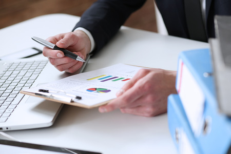 Hand of businessman in suit filling and signing with silver pen partnership agreement form clipped to pad closeup. Management training course, some important document, team leader ambition conceptの写真素材