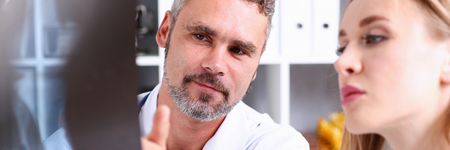 Mature male doctor hold in arm and look at xray photography discussing it with female patient portrait. Bone disease exam, medic assistance, cancer test, healthy lifestyle, hospital practice conceptのeditorial素材