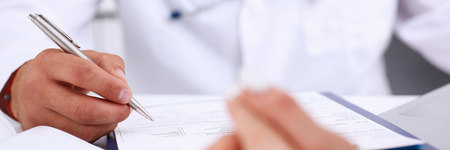 Male doctor arm hold silver pen filling patient complaints list clipped to pad. Physical, problem exam, er, disease prevention, ward round, visitor check, prescribe remedy, healthy lifestyle conceptの写真素材
