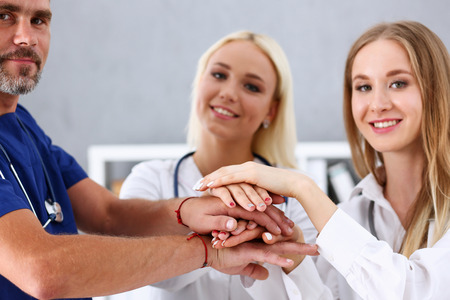 Group of doctor crossed arms in pile for win closeup. High five, cooperation initiative achievement, heap, stack, people cure strategy, colleague competition, heal alliance, hospital visit conceptの写真素材