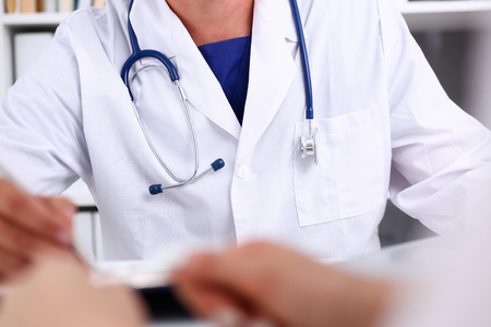 Stethoscope head lying on doctor chest wearing blue uniform closeup. Physical exam, patient reception, ward round, disease prevention, consultant, profession, pulse measure, healthy lifestyle conceptの写真素材