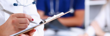 Female doctor hold clipboard pad and fill medical history list with silver pen. Physical, illness prevention, 911, prescribe remedy, ward round, therapeutist assistance, healthy lifestyle conceptの写真素材