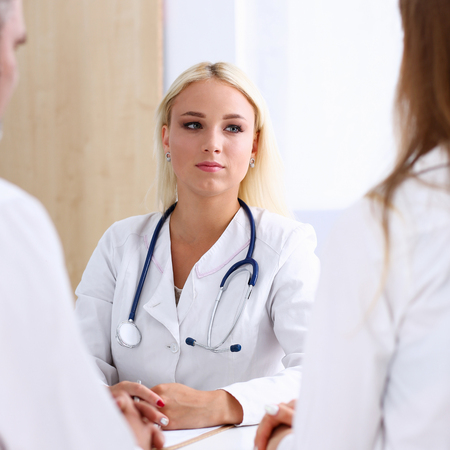 Female family doctor listen carefully young couple in office. Motherhood and child delivery IVF, new life, abortion, therapeutist reception service, physical, hope emotion, hospital expectationのeditorial素材