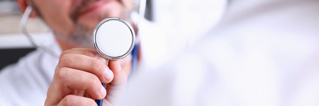 Male doctor hold in arm stethoscope head in front of his chest going to listen patient. Tool shop or store, physical and disease prevention, er consultant, 911, pulse measure, healthy lifestyleの写真素材
