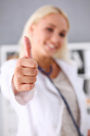 Beautiful smiling female doctor showing OK or confirm sign with thumb up closeup. High level therapeutist consultation, best treatment, healthy lifestyle, satisfied patient, physical exam conceptの写真素材