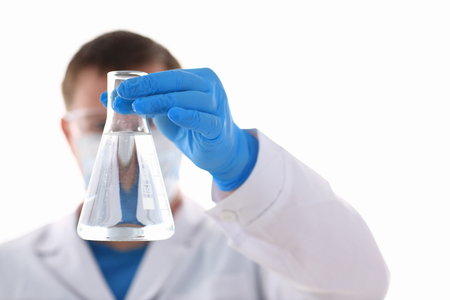 A male chemist holds test tube of glass in his hand overflows a liquid solution of potassium permanganate conducts an analysis of water samples versions of reagents using chemical manufacturingの写真素材