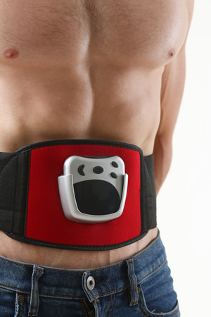 Athletic folded man uses an electric belt simulator for training a pressの写真素材