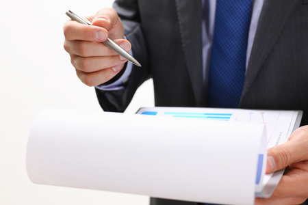 Hand of businessman in suit filling and signing with silver pen partnership agreement form clipped to pad closeup. Management training course, some important document, team leader ambition conceptの写真素材