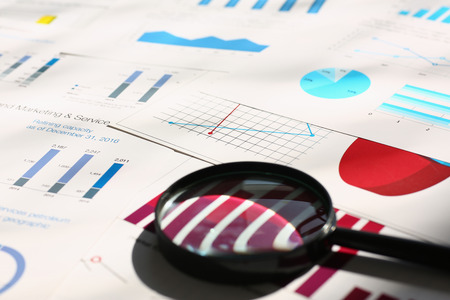 Financial statistics documents on lens and pen office table closeup. Internal Revenue Service inspector sum check, irs investigation, exchange market, earnings, savings, loan and credit conceptの写真素材