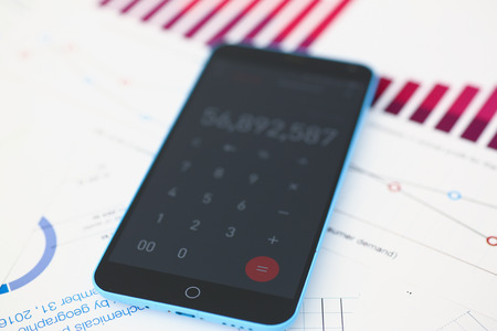 Smartphone calculator and financial statistics ondisplay tablet at office table closeup. Internal Revenue Service inspector sum check, irs investigation, earnings, savings, loan and credit conceptの写真素材