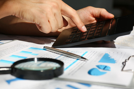 Black calculator and financial statistics on infographics at office table closeup. Internal Revenue Service inspector sum check, irs investigation, earnings, savings, loan and credit conceptの写真素材