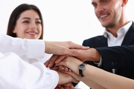 Group of people in suits crossed hands in pile for win closeup. White collar leadership, high five,...