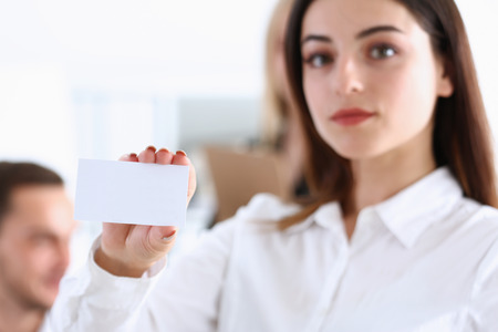Female hand in suit give blank calling card to visitor closeup. White collar partners company name exchange, executive or ceo introducing at conference, product consultant, sale clerk conceptの写真素材