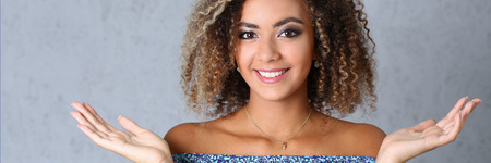 Beautiful black woman portrait. Hands up and smiling beauty fashion style mulatto curly hair with white locks eyes look into the cameraの写真素材