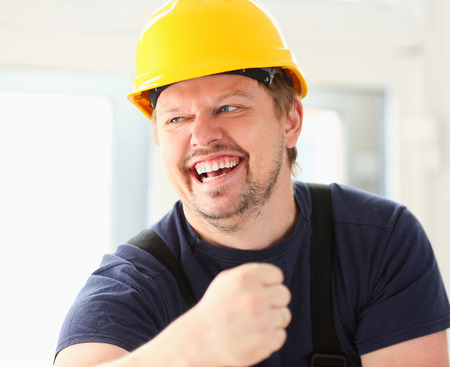 Smiling funny worker in yellow helmet posing. Manual job workplace, DIY inspiration, improvement, fix shop, hard hat, joinery startup idea, industrial education, profession career conceptの写真素材
