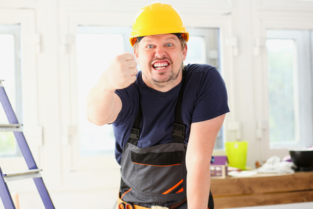 Smiling funny worker in yellow helmet posing. Manual job workplace, DIY inspiration, improvement, fix shop, hard hat, joinery startup idea, industrial education, profession career conceptの写真素材